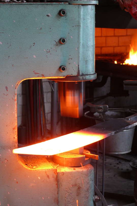 Der erhitzte Stahl wird unter dem Maschinen-Hammer heiß geschmiedet und in Form gebracht